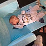 baby, infant, onesie, blue_changing_pad, baby_sandals, footwear, slippers, floor, person, child, lying_down, indoor, clothing, baby_gear, cute, sleepwear, text_on_clothing, human, newborn, baby_boy
