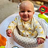 baby, child, smiling, giraffe_pattern, baby_seat, cushion, indoor, happy, cute, infant, clothing, portrait, person, skin, head, hand, face, furniture, toy, bright