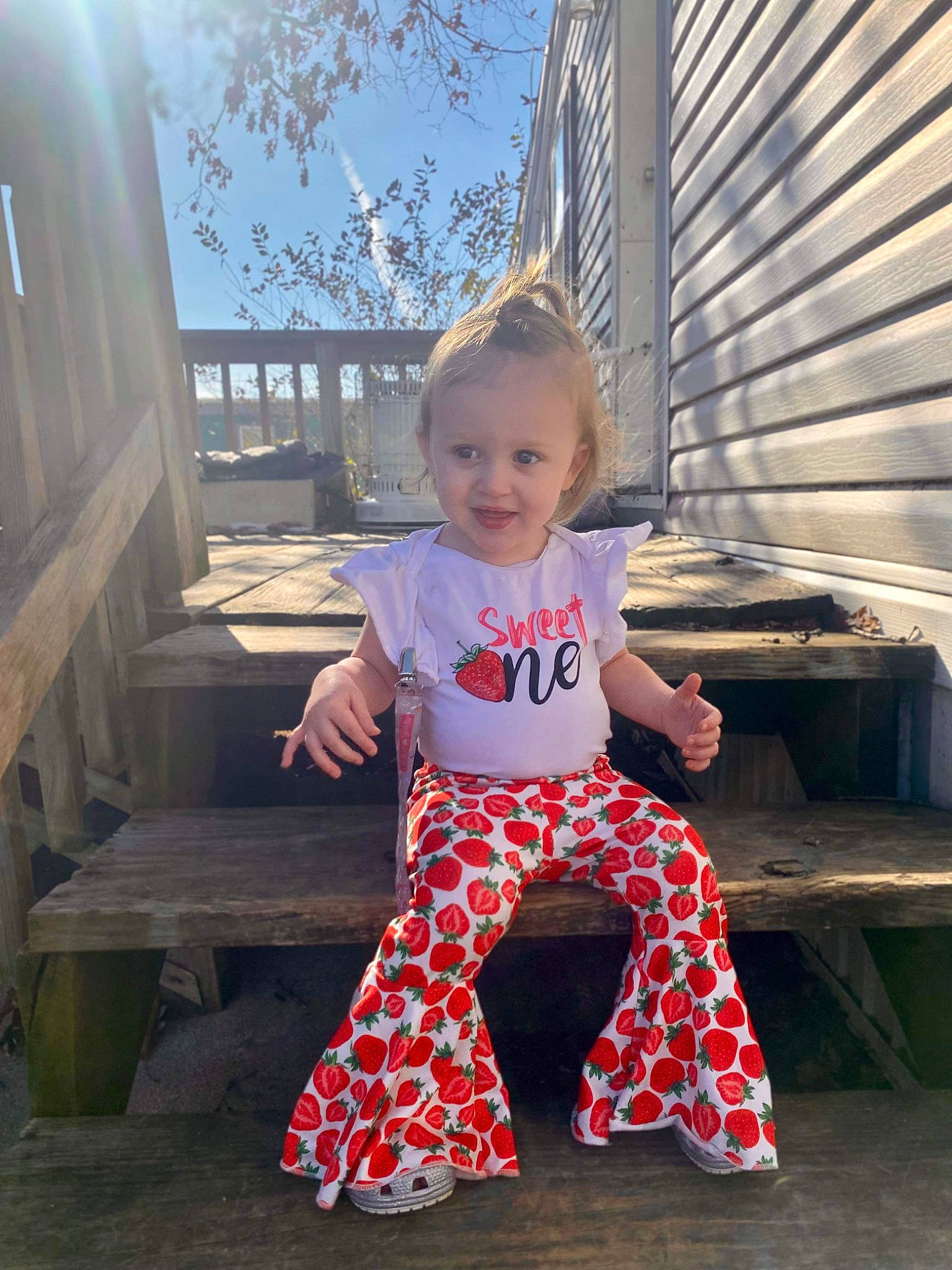 Kyla is registered to the contest to win money with this photo: baby, baby_toddler_clothing, child, electric_blue, flash_photography, fun, happy, joy, leisure, magenta, pattern, person, sitting, sky, sleeve, smile, t_shirt, toddler, travel, tree