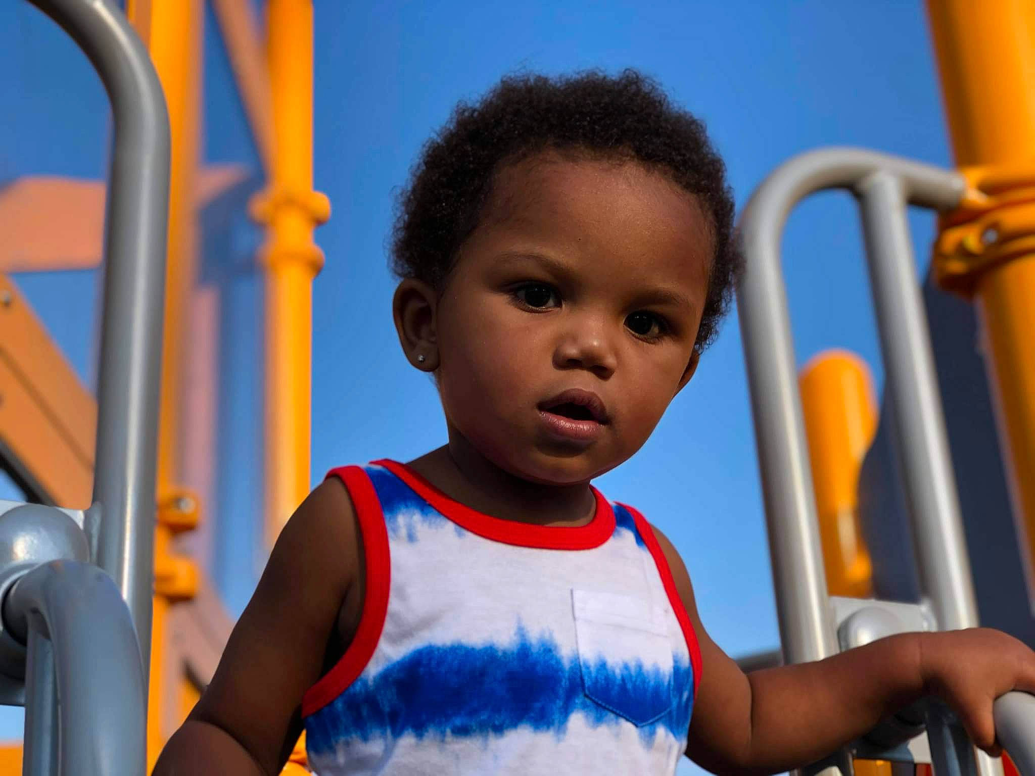 Kay'Vion joined the competition — help win amazing prizes! azure, baby_toddler_clothing, blue, child, facial_expression, fun, happy, leisure, nose, orange, organ, outdoor_play_equipment, people, person, photograph, playground, red, sky, standing, toddler