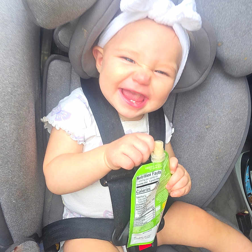 Autumn Faith is registered to the contest to win money with this photo: baby, car_seat, child, smiling, headband, toy, snack_pouch, seatbelt, happy, infant, clothing, indoor, cute, playful, child_seat, sitting, bright, cheerful, young, accessory