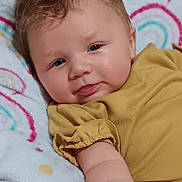 Bonnie joined the competition — help win amazing prizes! baby, infant, child, smile, face, blue_eyes, hair, blanket, rainbow_pattern, mustard_clothing, arm, cute, indoors, soft_texture, portrait, skin, hand, comfort, lying_down, happy