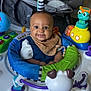 activity_center, baby, blue, child, clothing, colorful, face, floor, green, happy, head, indoor, infant, orange, person, play, seat, smiling, toy, yellow