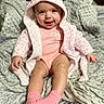apparel, baby, blanket, child, cozy, cute, cute_expression, happy, hooded_jacket, indoors, infant, person, pink_clothing, portrait, seated, smile, socks, soft_texture, warm, young