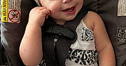 Malina is registered to the contest to win money with this photo: baby, black_and_white_clothing, bottle, car_seat, child, cute, face, happy, headband, holding, indoors, infant, person, playful, portrait, seatbelt, sitting, smiling, white_headband, young_child