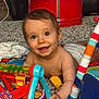 baby, smiling, toys, colorful, indoor, floor, play, child, diaper, happy, cute, person, hand, face, eyes, wooden_floor, fabric, plastic, red, blue