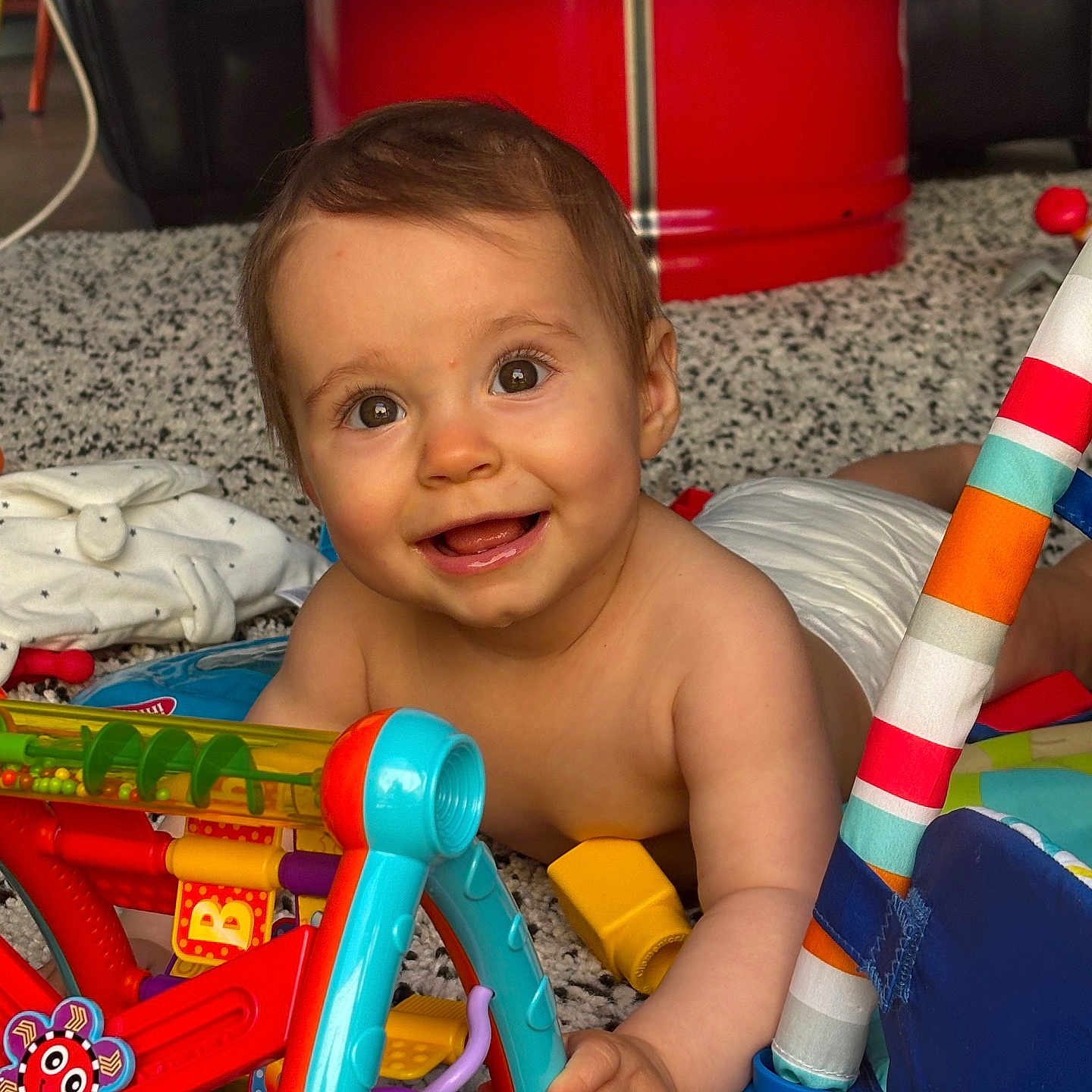 Léna a rejoint le concours — aidez-le/la à gagner de superbes lots ! baby, blue, child, colorful, cute, diaper, eyes, fabric, face, floor, hand, happy, indoor, person, plastic, play, red, smiling, toys, wooden_floor