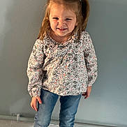 Lyza participe au concours pour gagner de l'argent avec cette photo : child, girl, pigtails, floral_blouse, jeans, standing, indoor, wall, floor, tiles, expression, scrunched_face, cute, casual_clothing, person, portrait, smile, hair, young, playful