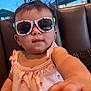 Genesis Rose is registered to the contest to win money with this photo: toddler, child, sunglasses, pink_dress, drool, curly_hair, indoor, booth, window, outdoor, umbrella, daylight, person, cute, fashion, baby, portrait, reaching_hand, seat, casual