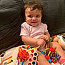 Genesis Rose joined the competition — help win amazing prizes! baby, child, smiling, curly_hair, pink_onesie, toy, colorful_toy, couch, indoor, happy, person, infant, play, sitting, cute, face, young_child, home, blanket, fun