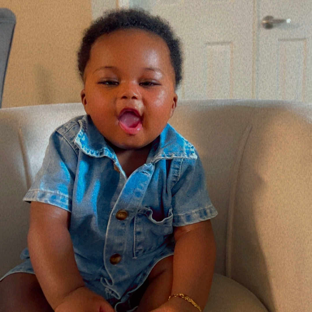 Joseph Fotsing joined the competition — help win amazing prizes! baby, bracelet, casual_clothing, chair, child, cute, denim_shirt, expression, footwear, furniture, happy, home, indoor, person, shoe, short_hair, sitting, skin, smiling, toddler