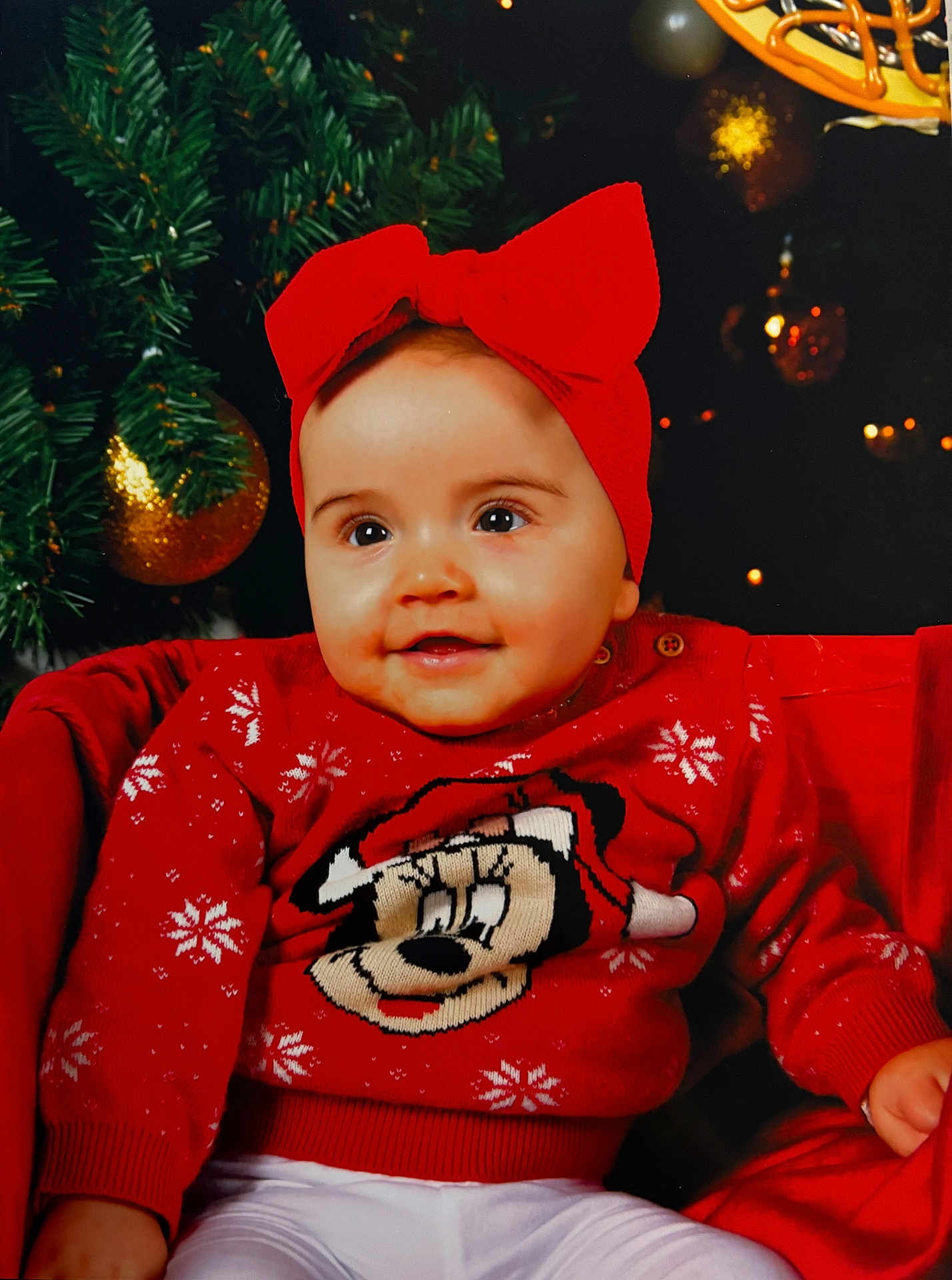 Ambre participe au concours pour gagner de l'argent avec cette photo : baby, celebration, child, christmas_tree, cute, decoration, festive, happy, headband, holiday, indoor, ornaments, person, portrait, red_bow, red_sweater, seasonal, sitting, smiling, white_pants