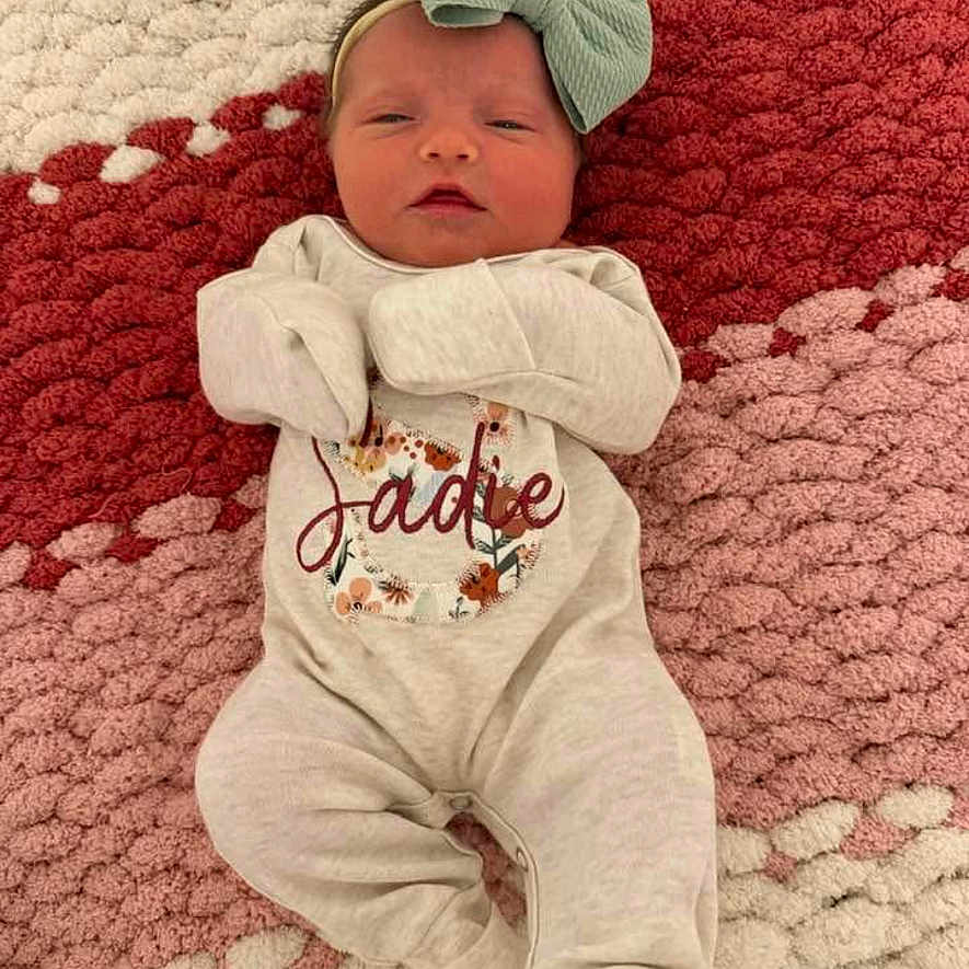 Sadie joined the competition — help win amazing prizes! newborn, baby, infant, onesie, headband, bow, blanket, pattern, texture, lying_down, sleeping, cute, cozy, child, face, clothing, soft_lighting, indoors, portrait, peaceful