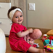 Anna participe au concours pour gagner de l'argent avec cette photo : barefoot, cabinet, casual, child, colorful_toys, cute, furniture, happy, headband, indoor, person, playtime, plush_octopus, red_dress, room, smiling, toddler, toy, wooden_floor, young_child