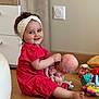 barefoot, cabinet, casual, child, colorful_toys, cute, furniture, happy, headband, indoor, person, playtime, plush_octopus, red_dress, room, smiling, toddler, toy, wooden_floor, young_child