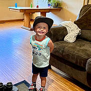 Jaxson joined the competition — help win amazing prizes! toddler, child, smiling, indoor, living_room, cap, sneakers, shorts, sleeveless_shirt, wood_floor, table, sofa, blanket, plant, window, photo_frames, binoculars, rug, happy, person