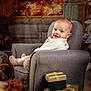 armchair, baby, carpet, child, christmas, cozy, cute, decorations, fireplace, furniture, gift_box, holiday, indoor, knitwear, living_room, plush, reindeer_slippers, smile, warm_lighting, wrapped_presents