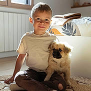 Côme participe au concours pour gagner de l'argent avec cette photo : child, boy, puppy, dog, indoor, sunlight, window, rug, bed, blanket, smile, casual_clothing, socks, floor, cozy, cute, pet, home, portrait, happy