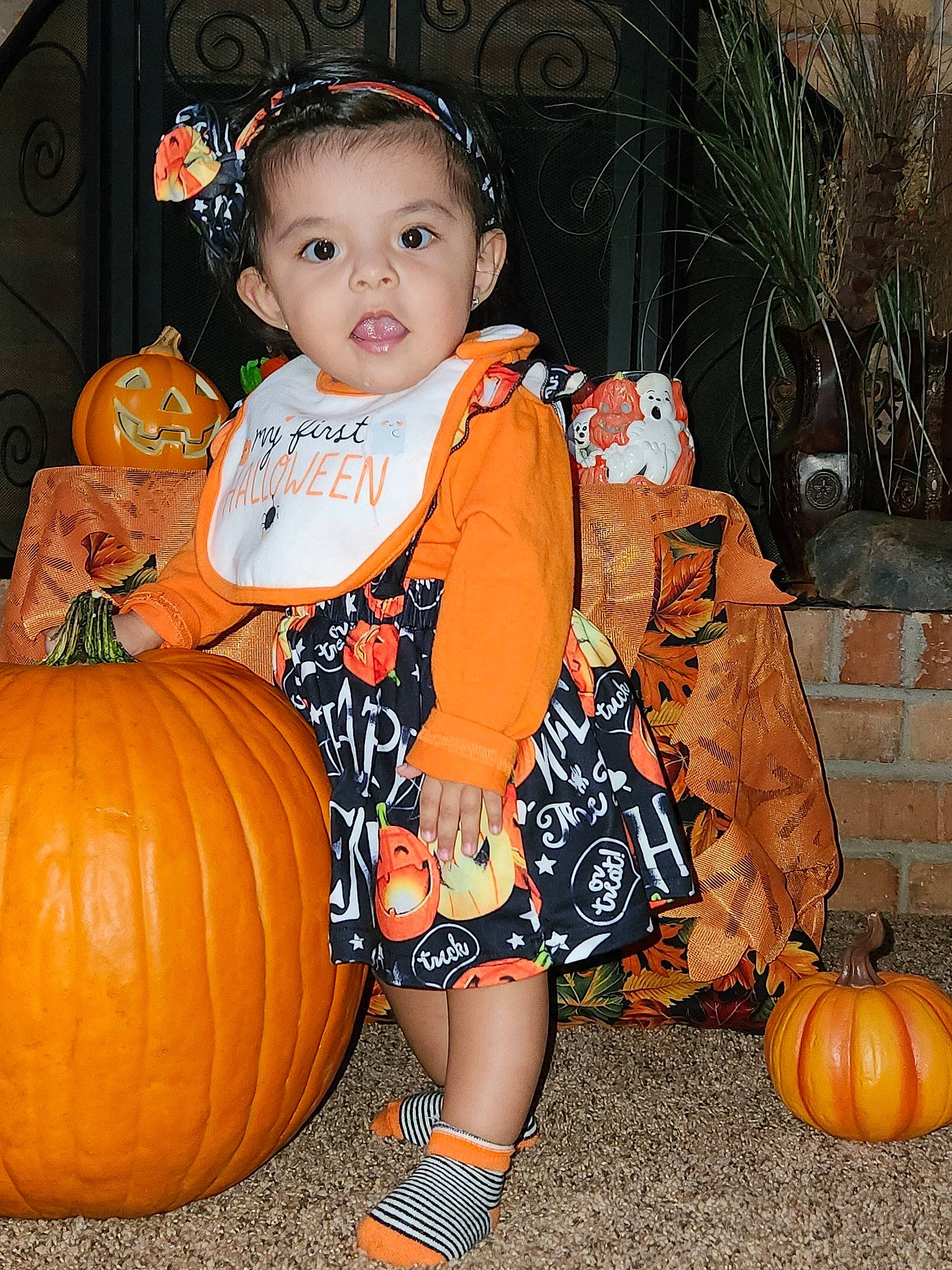 Alicia is registered to the contest to win money with this photo: baby, baby_toddler_clothing, black, calabaza, child, cucurbita, eye, facial_expression, fruit, gourd, happy, natural_foods, orange, person, plant, pumpkin, squash, standing, toddler, vegetable