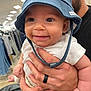 baby, child, hat, blue_hat, smile, happy, person, hand, adult, clothing_store, shirt, white_shirt, ring, black_ring, holding, retail, shopping, aisle, indoor, face