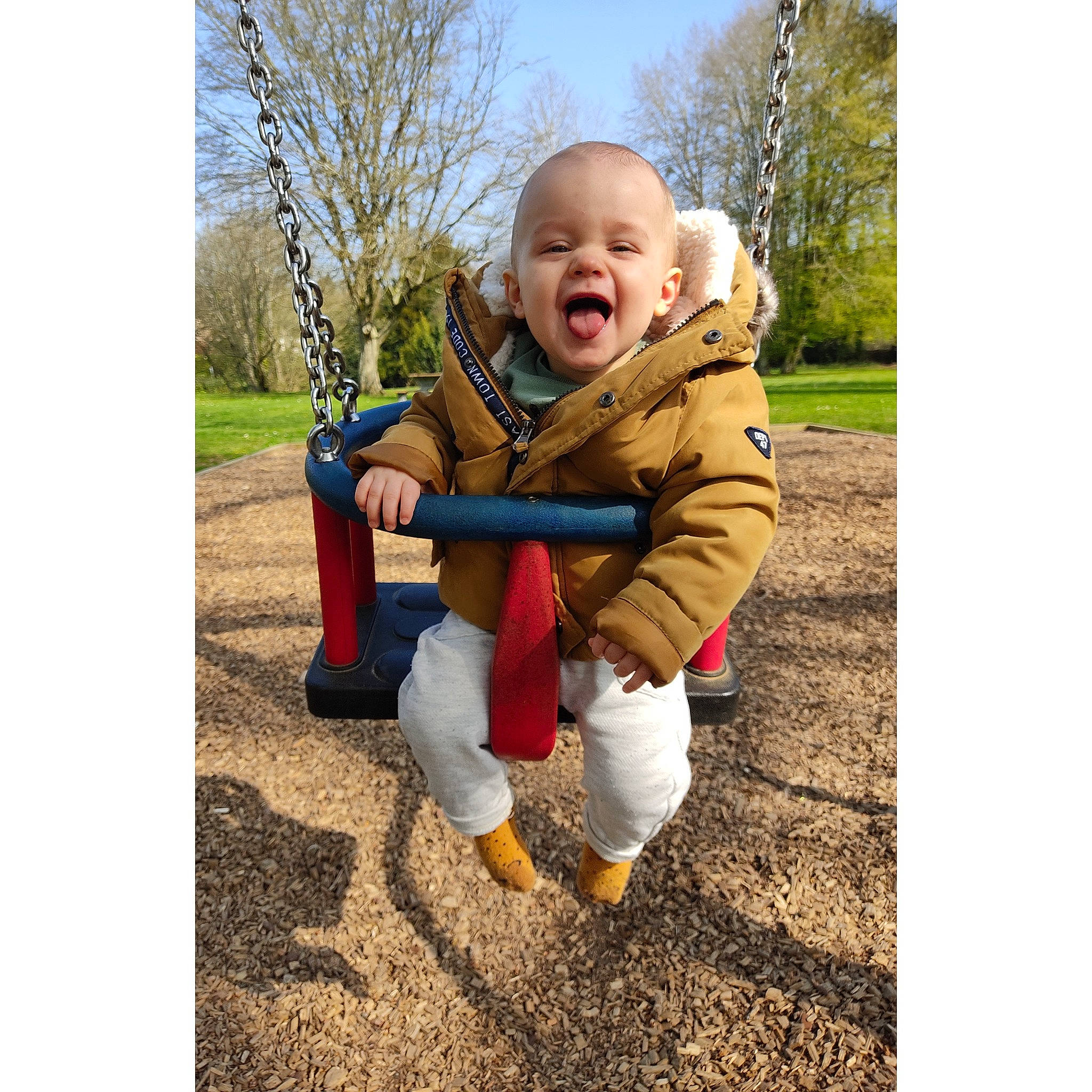 Raphaël a rejoint le concours — aidez-le/la à gagner de superbes lots ! baby, baby_toddler_clothing, fun, gesture, grass, happy, human_body, jacket, outerwear, people_in_nature, person, plant, sitting, sky, sleeve, smile, sneakers, swing, toddler, tree