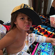 Valeriah joined the competition — help win amazing prizes! child, cap, tablet, playing, tongue_out, blanket, pajamas, indoor, popcorn, person, face, hand, colorful, pattern, bedroom, fun, casual, relaxed, technology, cute