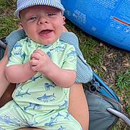 Ryder joined the competition — help win amazing prizes! baby, child, smiling, cap, hat, shark_pattern, outdoor, grass, inflatable_pool, clothing, person, lap, summer, happy, cute, clapping, seat, fabric, nature, playful