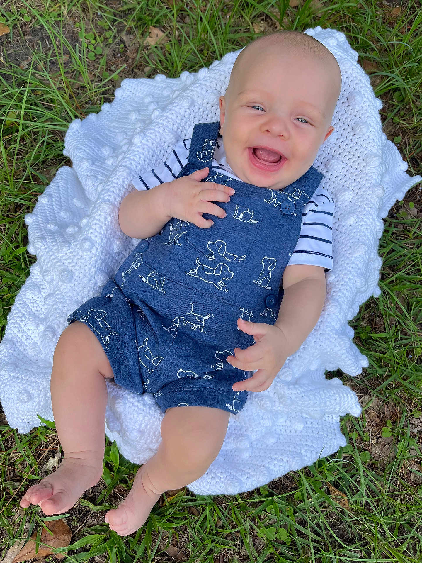 Ryder is registered to the contest to win money with this photo: baby, infant, smiling, laughing, outdoor, grass, blanket, knitted, blue_romper, dog_prints, striped_shirt, barefoot, cute, happy, child, person, nature, summer, portrait, closeup
