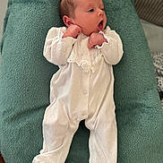 Cléo participe au concours pour gagner de l'argent avec cette photo : baby, infant, white_onesie, cushion, soft_texture, lying_down, curious_expression, small_hands, newborn, indoors, fabric, sleepwear, cozy, portrait, child, cute, peaceful, relaxed, head, face
