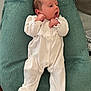 baby, infant, white_onesie, cushion, soft_texture, lying_down, curious_expression, small_hands, newborn, indoors, fabric, sleepwear, cozy, portrait, child, cute, peaceful, relaxed, head, face