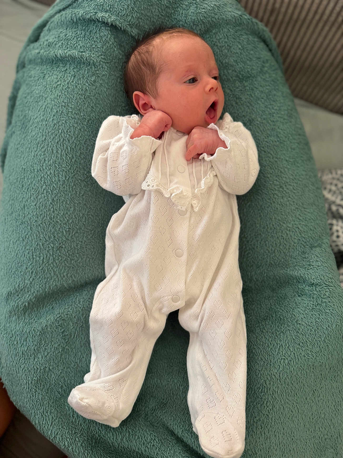 Cléo participe au concours pour gagner de l'argent avec cette photo : baby, infant, white_onesie, cushion, soft_texture, lying_down, curious_expression, small_hands, newborn, indoors, fabric, sleepwear, cozy, portrait, child, cute, peaceful, relaxed, head, face