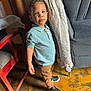 Pedro is registered to the contest to win money with this photo: boy, bracelet, casual, chair, child, clothing, couch, curtain, expression, floor, furniture, indoor, necklace, pants, person, polo_shirt, portrait, sneakers, standing, young