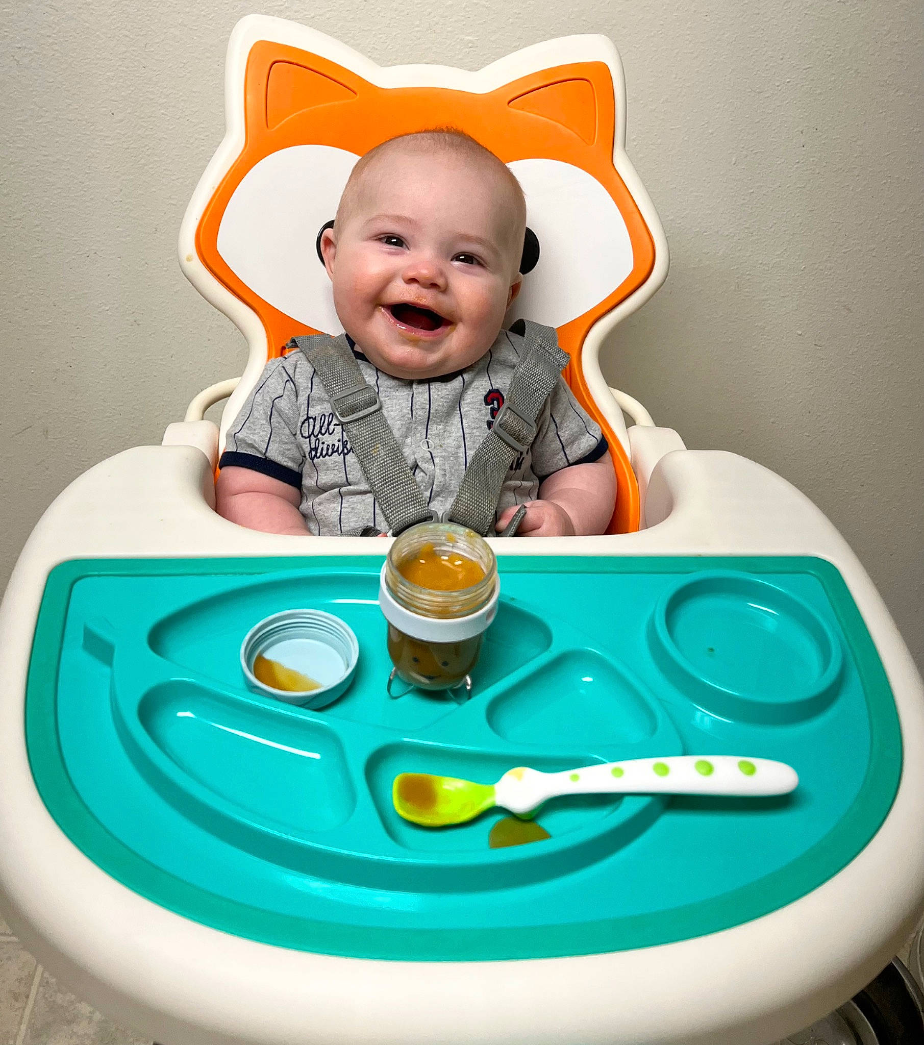 Tatum is registered to the contest to win money with this photo: baby, baby_playing_with_toys, baby_toddler_clothing, child, dishware, drinkware, facial_expression, fun, green, happy, joy, orange, person, plate, product, serveware, sitting, sleeve, smile, t_shirt