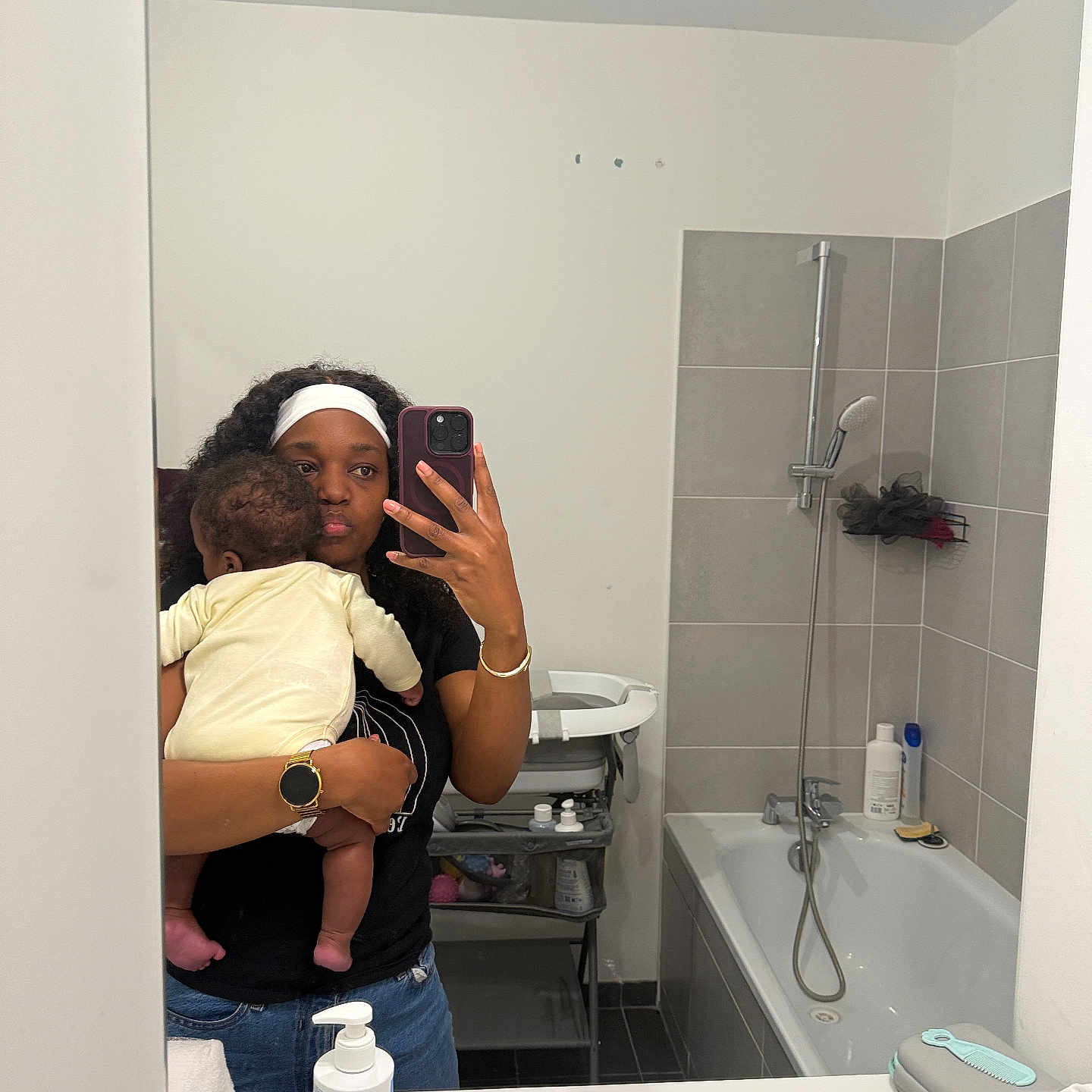 Isaac-Martins a rejoint le concours — aidez-le/la à gagner de superbes lots ! woman, baby, mirror, bathroom, selfie, shower, bathtub, sink, soap, towel, headband, watch, phone, tiles, basket, storage_shelf, clothing, person, reflection, indoor