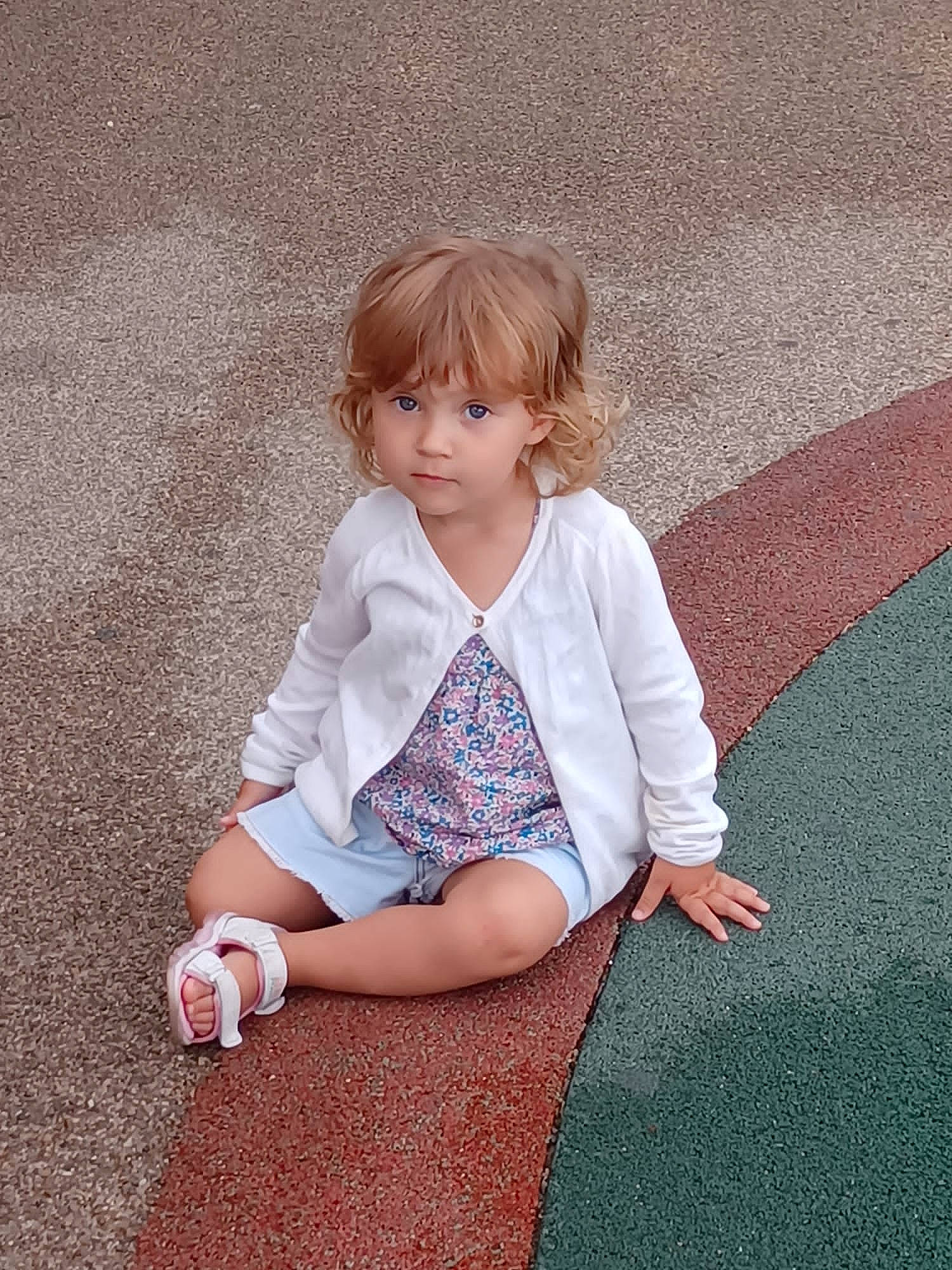 Lucy a rejoint le concours — aidez-le/la à gagner de superbes lots ! baby_toddler_clothing, brown_hair, child, face, flooring, foot, grass, human_body, human_leg, knee, leg, magenta, pattern, people_in_nature, person, sitting, sleeve, t_shirt, thigh, toddler