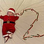 baby, blanket, candy_cane, celebration, child, christmas, cute, decoration, festive, footwear, holiday, indoors, infant, lying_down, portrait, red_clothing, santa_claus_costume, seasonal, smiling_face, soft_texture