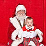 baby, child, santa_claus, red_background, holiday, christmas, festive_clothing, plaid, bow_tie, smiling, portrait, white_beard, glasses, white_gloves, red_suit, indoor, happy, seated, person, celebration