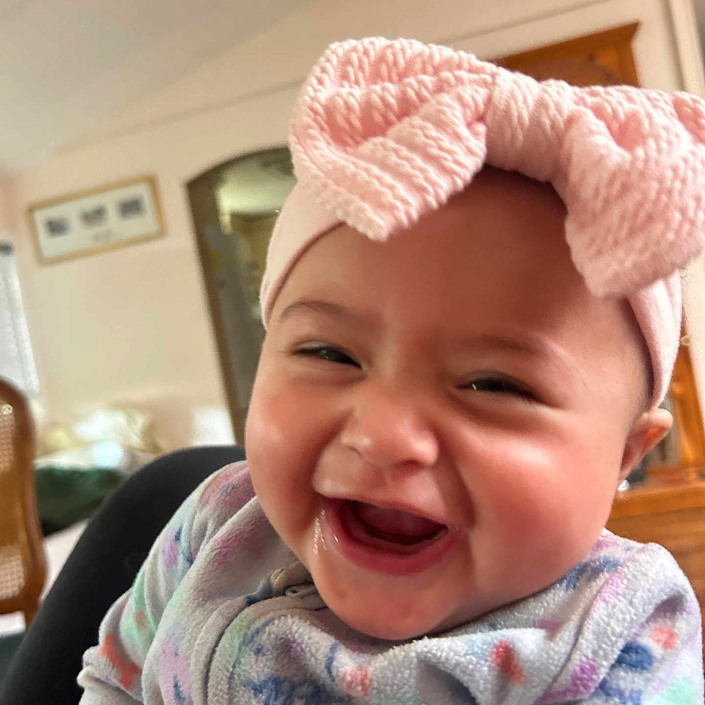 Leah joined the competition — help win amazing prizes! baby, cheeks, child, close_up, clothing, cute, face, fleece, hand, happy, headband, home, indoors, infant, joy, laughing, person, pink_bow, seated, smiling