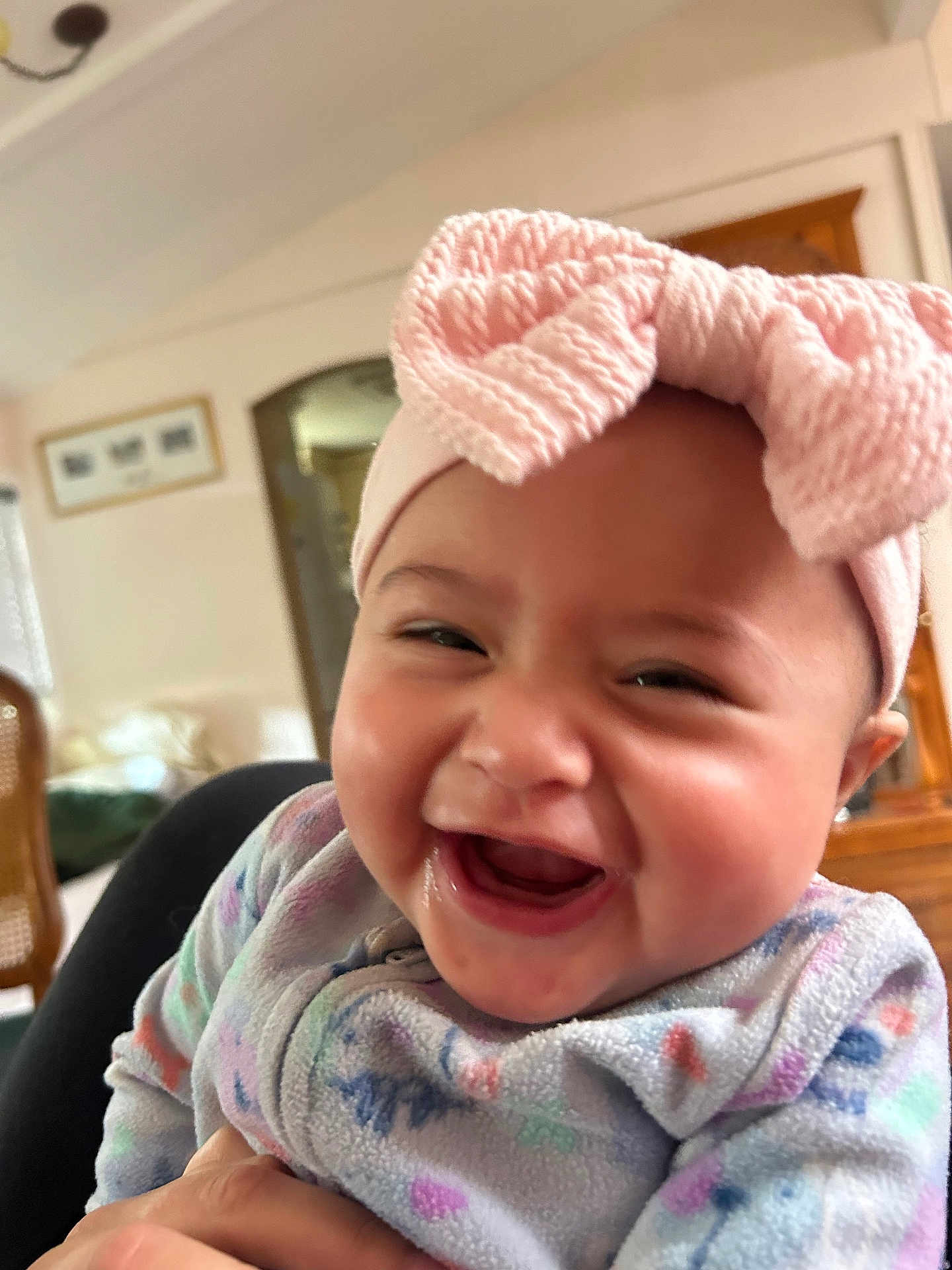 Leah joined the competition — help win amazing prizes! baby, smiling, laughing, infant, headband, pink_bow, fleece, clothing, person, close_up, indoors, home, joy, cute, happy, face, cheeks, hand, seated, child