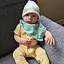 Alexander is registered to the contest to win money with this photo: baby, infant, onesie, hat, bib, couch, gray_couch, sitting, indoor, child, cute, looking_at_camera, clothing, fabric, furniture, person, young_child, comfortable, casual, portrait