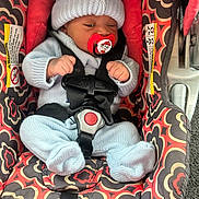 Joeray joined the competition — help win amazing prizes! baby, infant, car_seat, pacifier, knitted_hat, knitted_clothing, safety_harness, patterned_fabric, red, blue, child, seat_belt, indoor, cute, newborn, small_hands, small_feet, resting, child_safety, car_accessory