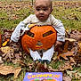 Jahmir joined the competition — help win amazing prizes! autumn_leaves, baby, book, carved_pumpkin, child, costume, cute, expression, face, fall, grass, holiday, leaf, nature, orange, outdoor, pumpkin, seasonal, sitting, smiling