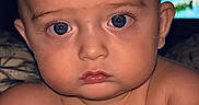 Myles is registered to the contest to win money with this photo: baby, bedroom, blanket, blue_eyes, candid, child, closeup, comfort, curious, expression, face, hair, indoor, infant, person, portrait, resting, skin, soft_lighting, young
