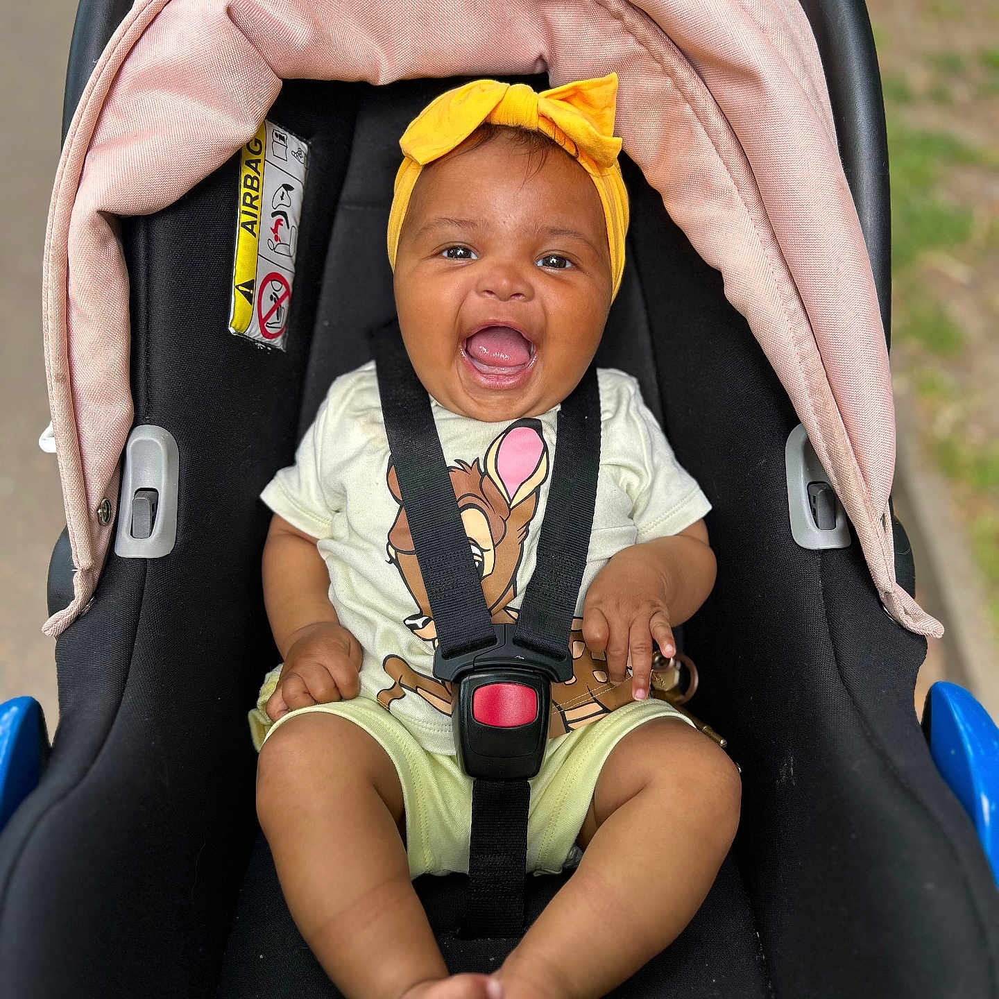 Iris joined the competition — help win amazing prizes! baby, car_seat, cartoon, child, cute, deer, feet, happy, headband, infant, outdoor, person, pink, portrait, safety, seatbelt, sitting, smiling, tshirt, yellow