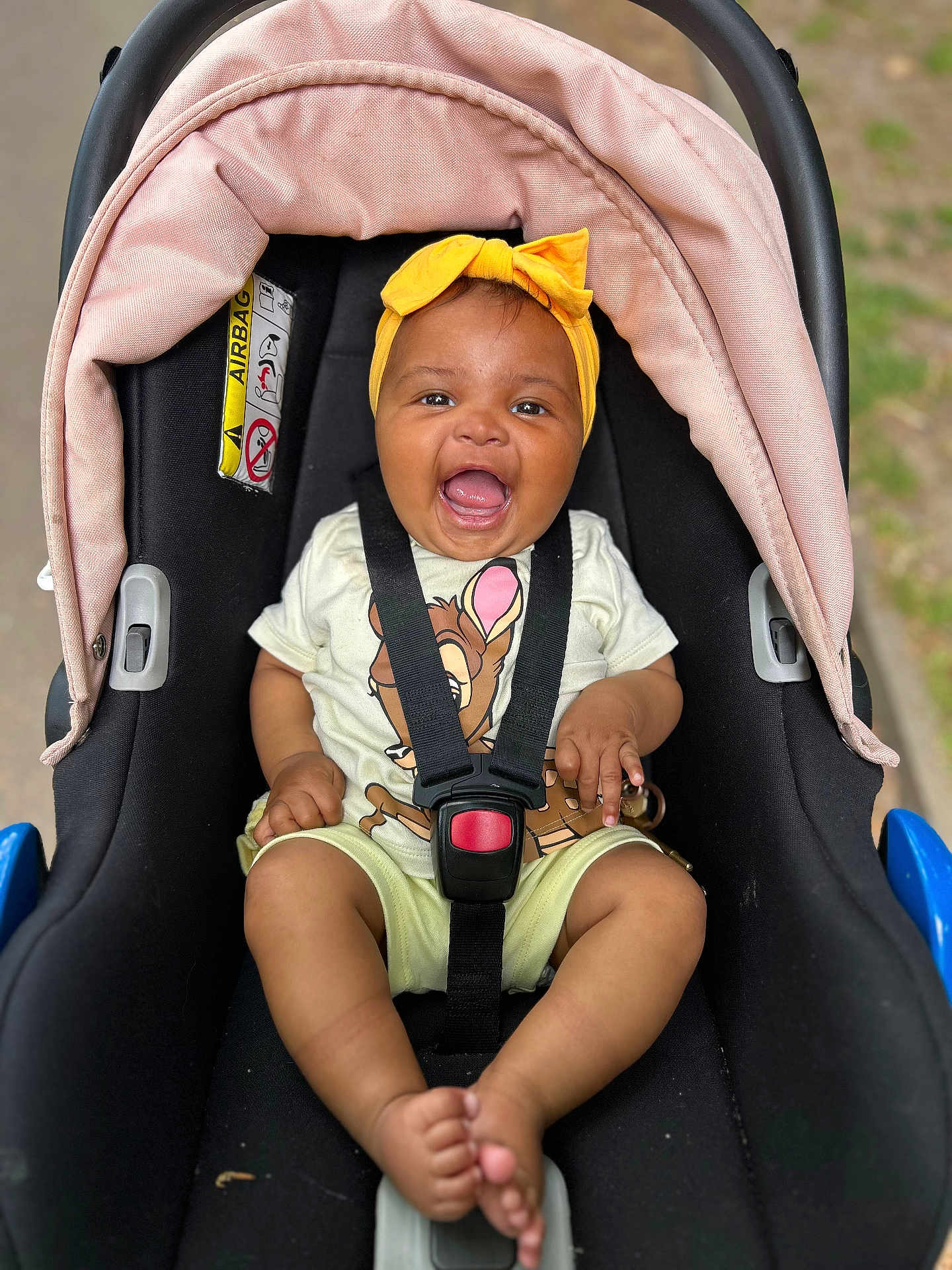 Iris joined the competition — help win amazing prizes! baby, car_seat, child, smiling, headband, yellow, tshirt, cartoon, deer, happy, infant, seatbelt, outdoor, cute, pink, feet, portrait, person, sitting, safety