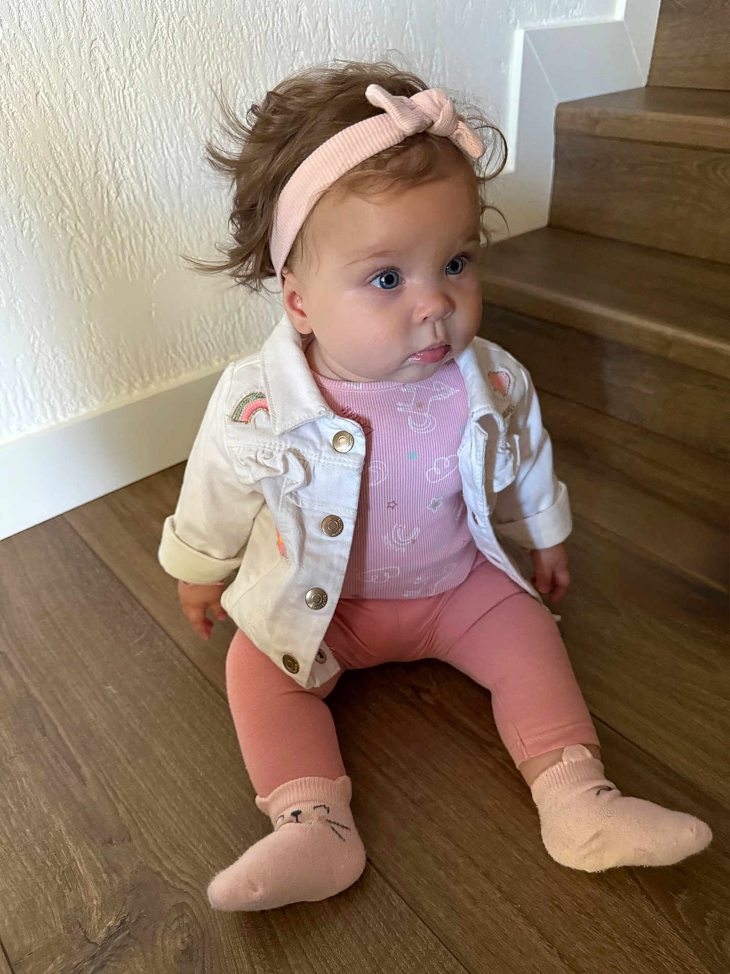 Angelina participe au concours pour gagner de l'argent avec cette photo : baby, child, indoor, stairs, wooden_floor, pink_clothing, headband, jacket, socks, cute, sitting, portrait, infant, person, face, blue_eyes, curly_hair, expression, floor, casual_wear