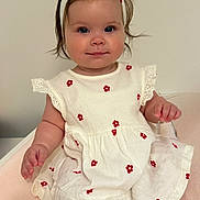 Angelina participe au concours pour gagner de l'argent avec cette photo : baby, child, infant, girl, dress, headband, white, red, flowers, sitting, soft_surface, cute, portrait, smile, skin, hand, foot, indoors, calm, curious