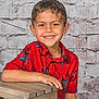 child, boy, smile, red_shirt, spiderman, short_hair, wooden_stool, brick_wall, casual, happy, portrait, indoor, sitting, hand, clothing, person, background, cute, youth, relaxed