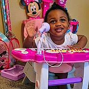 A'Leilah joined the competition — help win amazing prizes! toddler, child, toy_keyboard, microphone, minnie_mouse, pink, purple, playroom, carpet, smiling, waving, indoor, child_toy, cute, happy, person, furniture, colorful, plastic, young_child