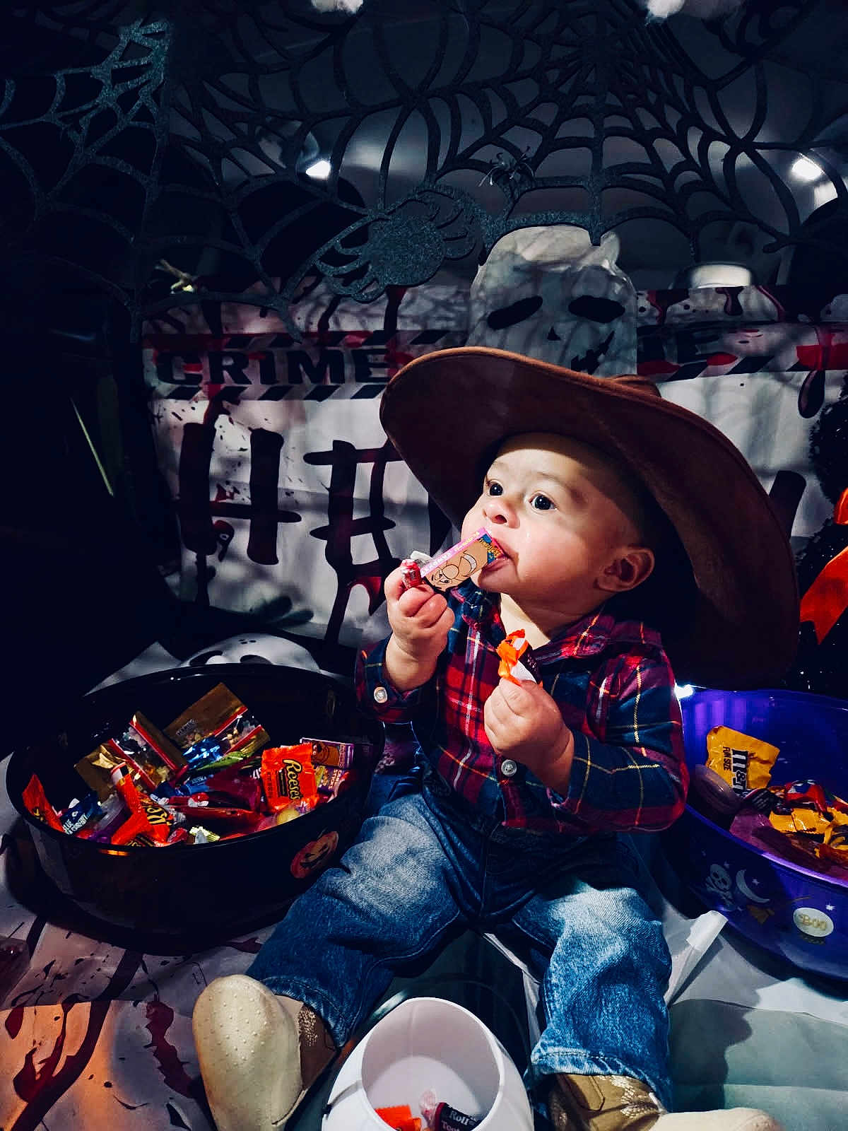 Dakota is registered to the contest to win money with this photo: toddler, child, candy, halloween, costume, cowboy_hat, plaid_shirt, jeans, boots, bowl, decorations, spider_web, skull, pumpkin, indoor, party, celebration, cute, holiday, treats